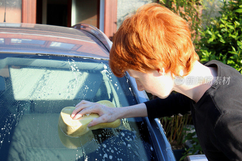 十几岁的男孩用海绵/洗车机清洗汽车挡风玻璃